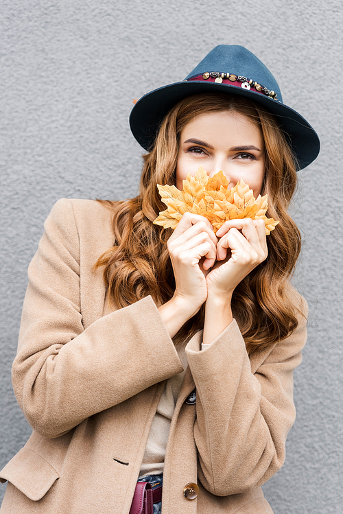 유토이미지 attractive woman in blue hat and holding yellow leaves