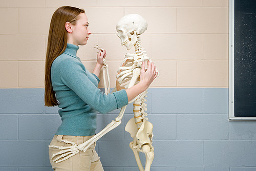 Female student dancing with human skeleton