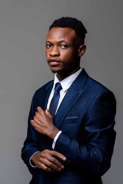 Young handsome African man wearing formal business suit  isolated on studio gray background