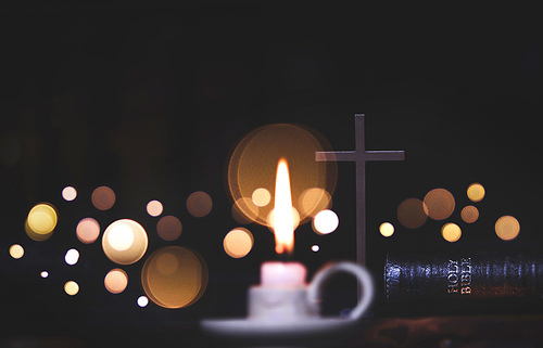거룩한 예수그리스도의 십자가와 성경책 그리고 밝은 크리스마스 불빛 보케와 양초 배경
