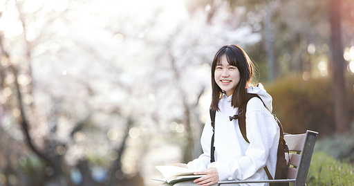 학교 공원 벤치에 앉아 책을 읽으며 공부하는 대학생과 가방을 메고 밝게 웃고있는 고등 학생 컨셉