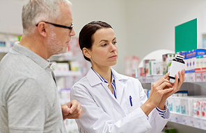 medicine, pharmaceutics, health care and people concept - pharmacist showing drug to senior man customer at drugstore