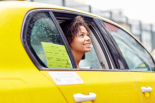 business trip, transportation and people concept - young smiling african american woman driving in taxi at city street