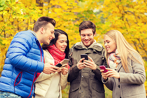 season, people, technology and friendship concept - group of smiling friends with smartphones in autumn park