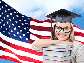 education, high school, knowledge and people concept - picture of happy student girl or woman in trencher cap with stack of books over american flag background