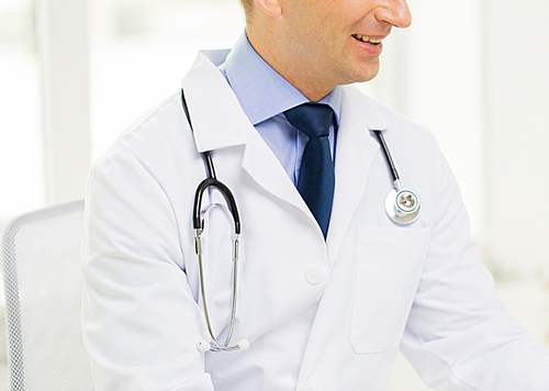 medicine, health care, people and profession concept - close up of happy male doctor with stethoscope at medical office in hospital