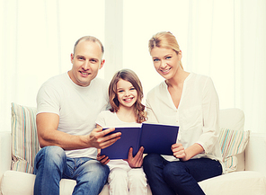 family, child and home concept - smiling parents and little girl with book at home