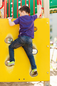summer, childhood, leisure and people concept - happy little boy on children playground climbing frame from back
