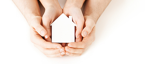 real estate and family home concept - closeup picture of male and female hands holding white blank paper house