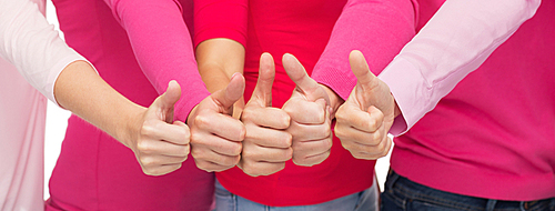 health care, people, gesture, breast cancer awareness and feminism concept - close up of women in pink shirts showing thumbs up