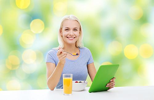 healthy eating, ing and people concept - smiling young woman with tablet pc computer eating breakfast over summer green holidays lights background