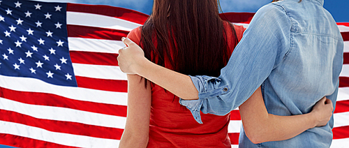 people, homosexuality, same-sex marriage, gay and love concept - close up of happy women couple hugging over american flag background