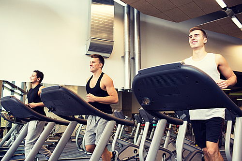 sport, fitness, lifestyle, technology and people concept - smiling men exercising on treadmill in gym