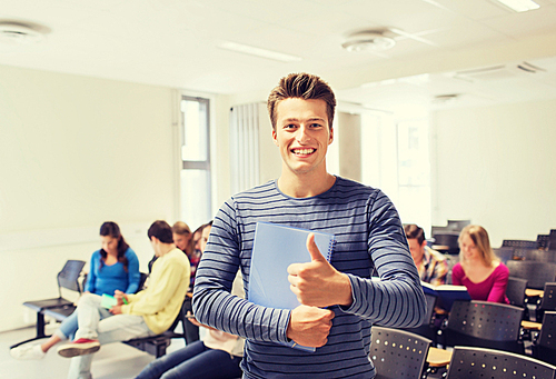 education, high school, gesture and people concept - group of smiling students with notepads showing thumbs up in lecture hall