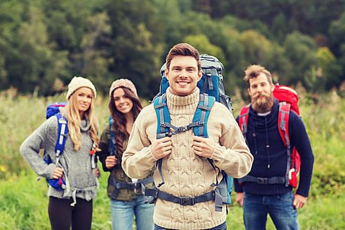 adventure, travel, tourism, hike and people concept - group of smiling friends standing with backpacks