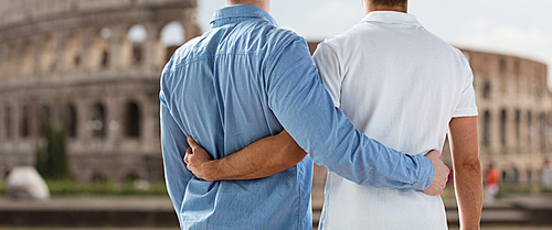 people, homosexuality, same-sex marriage, travel and love concept - close up of happy male gay couple hugging from back over coliseum in rome background