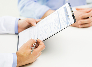 medicine, health care, people and prostate cancer concept - close up of f male doctor and patient hands with clipboard