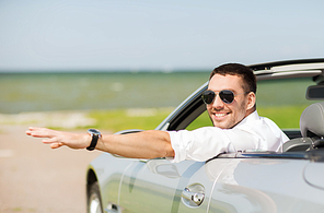 auto business, transport, leisure and people concept - happy man driving cabriolet car and waving hand outdoors