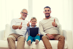 family, generation, technology and people concept - smiling father, son and grandfather sitting on couch with tablet pc computer showing thumbs up gesture at home