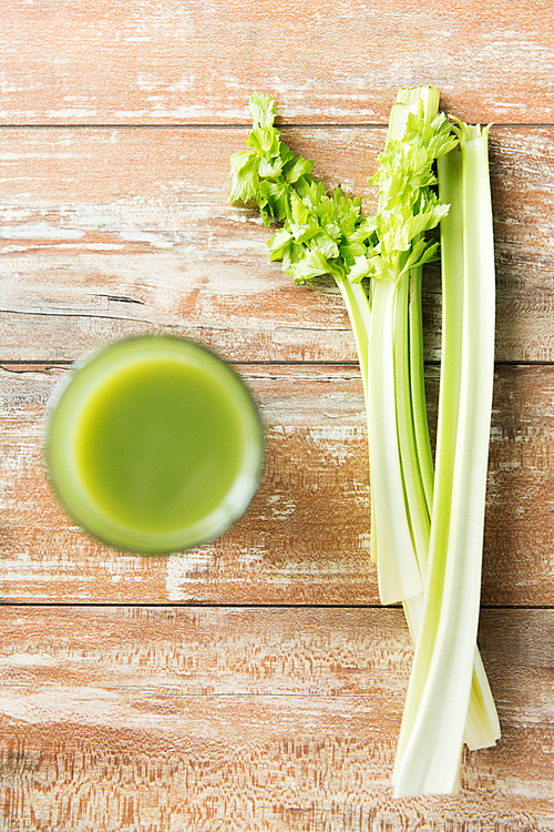 healthy eating, organic food and diet concept - close up of fresh green juice with celery on wooden table