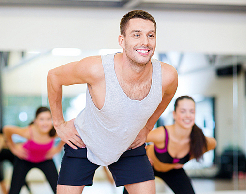 fitness, sport, training, gym and lifestyle concept - smiling male trainer working out in the gym