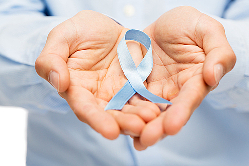 medicine, health care, gesture and people concept - close up of male hands holding blue prostate cancer awareness ribbon