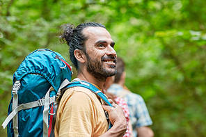 adventure, travel, tourism, hike and people concept - group of smiling friends walking with backpacks in woods