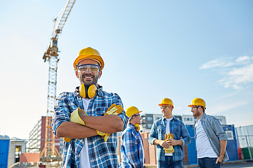 business, building, teamwork and people concept - group of smiling builders in hardhats at construction site