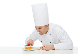 cooking, profession, haute cuisine, food and people concept - happy male chef cook decorating dessert