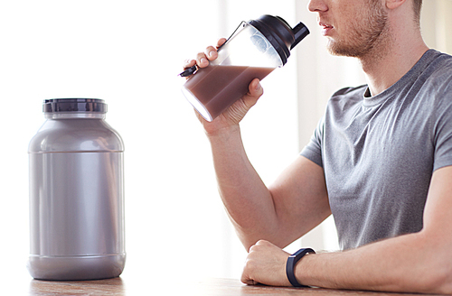 sport, fitness, healthy lifestyle and people concept - close up of man in fitness bracelet with jar and bottle drinking protein shake