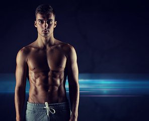 sport, bodybuilding, strength and people concept - young man with bare muscular torso standing over dark background