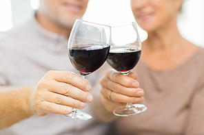 family, holidays, drinks, age and people concept - close up of happy senior couple clinking glasses with red wine at home