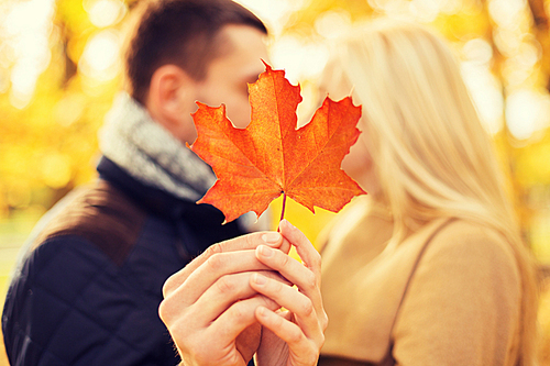 love, relationship, family and people concept - close up of couple with maple leaf kissing in autumn park