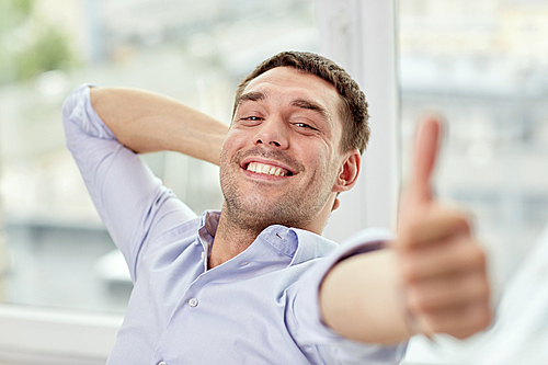 business, people and gesture concept - smiling man showing thumbs up at home or office