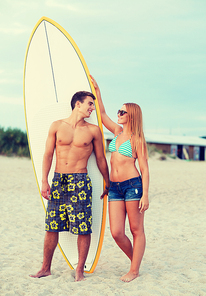 friendship, sea, summer vacation, water sport and people concept - smiling couple in swimwear and sunglasses with surfs on beach