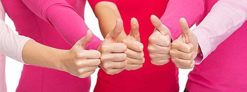 health care, people, gesture, breast cancer awareness and feminism concept - close up of women in pink shirts showing thumbs up