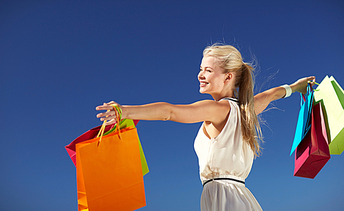 consumerism, sale and people concept - smiling woman with shopping bag rising hands