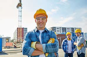 business, building, teamwork and people concept - group of smiling builders in hardhats at construction site