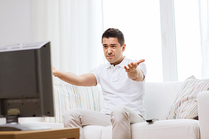 home, people, technology and entertainment concept - disappointed man watching sports on tv and supporting team at home