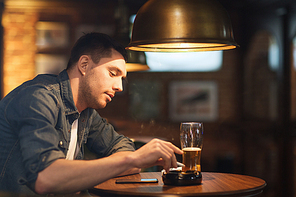 people and bad habits concept - man drinking beer and smoking and shaking off ashes of cigarette at bar or pub
