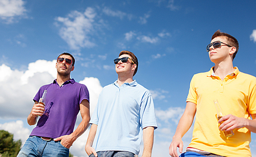 summer holidays, vacation, people and bachelor party concept - group of happy male friends drinking beer and walking along beach