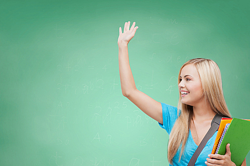 education, school, knowledge, gesture and people concept - smiling student with folders waving hand over green chalk board background