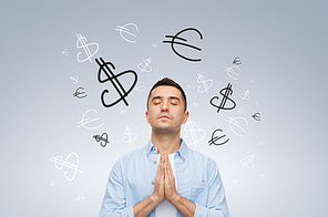 finance, business, faith and people concept - happy man with closed eyes praying to god with money currency symbols over gray background