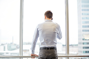 business, technology and people concept - businessman calling on smartphone and looking out office window