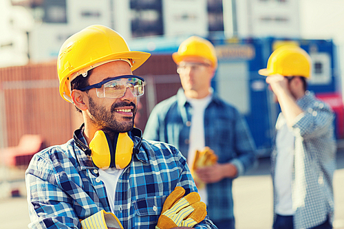 business, building, teamwork and people concept - group of smiling builders in hardhats outdoors