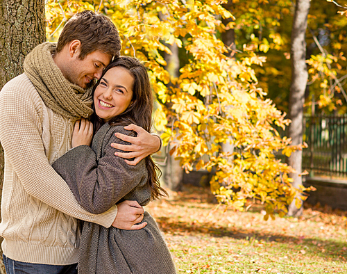 love, relationship, family, season and people concept - smiling couple hugging over autumn natural background