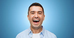 happiness, emotions and people concept - laughing man over blue background