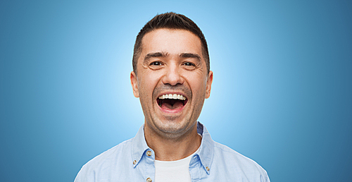 happiness, emotions and people concept - laughing man over blue background