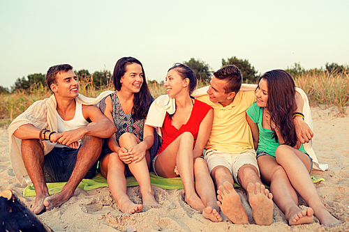 friendship, summer vacation, holidays, gesture and people concept - group of smiling friends sitting on beach