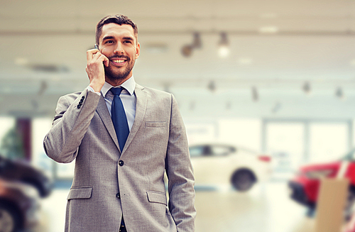 auto business, car sale, gesture and people concept - smiling businessman talking on smartphone over auto show background